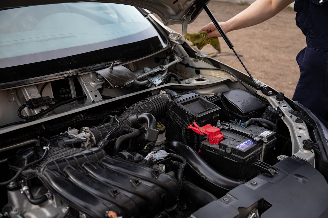 our-story Mechanic inspecting car engine bay and battery during routine maintenance.